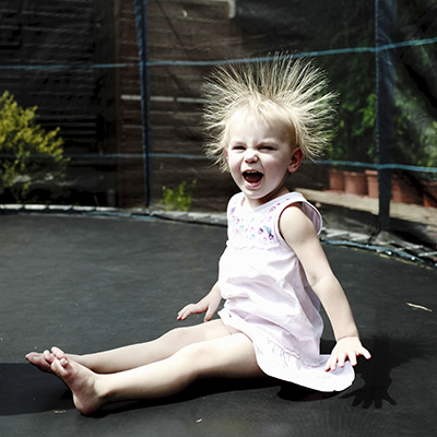 Toddler on trampoline with hair standing on end