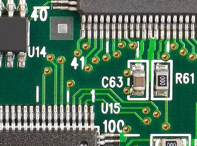 decoupling capacitor mounted on a printed circuit board through two closely spaced vias on the left side of the solder pads